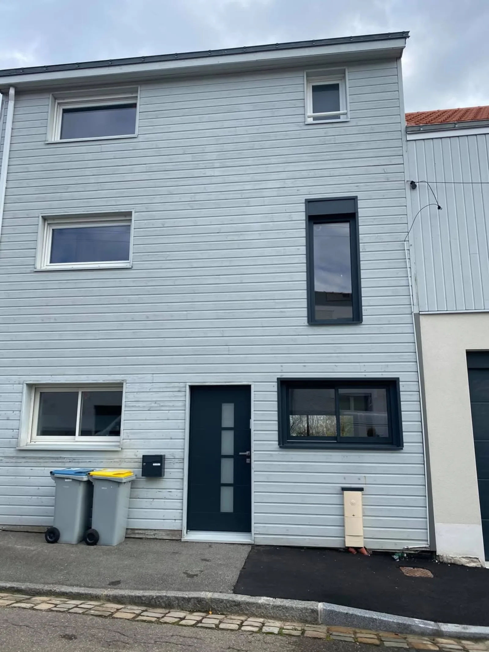 Maison de ville bardage bois gris avec fenêtres et porte aluminium