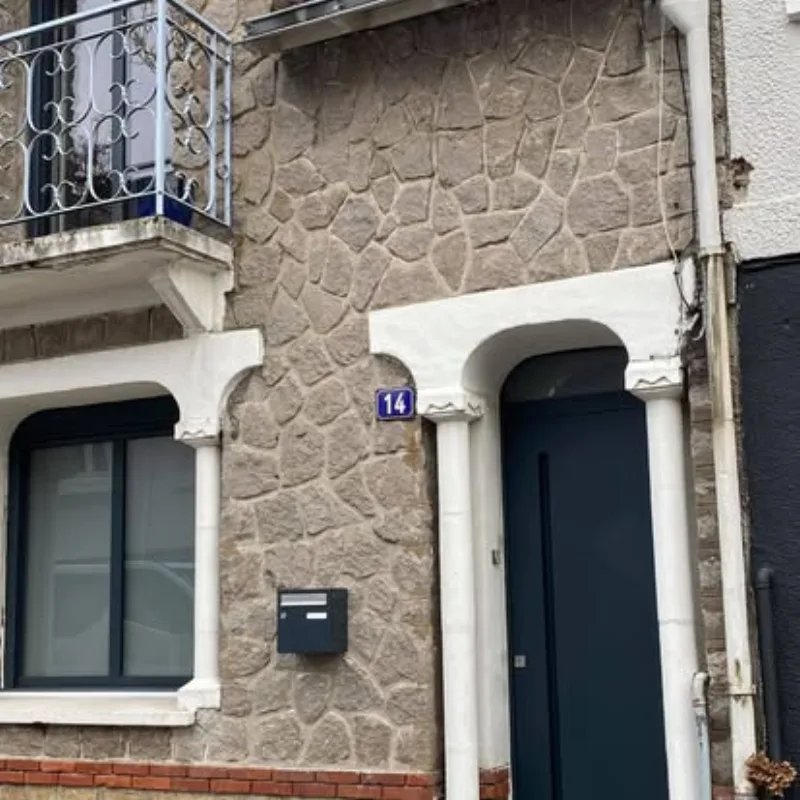 Façade en pierre rénovée avec porte d'entrée gris anthracite numéro 14