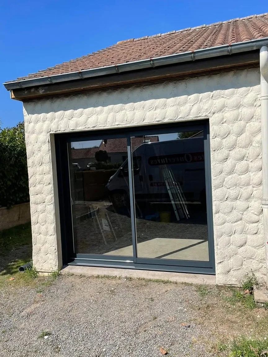 Baie vitrée coulissante aluminium anthracite sur façade pierre