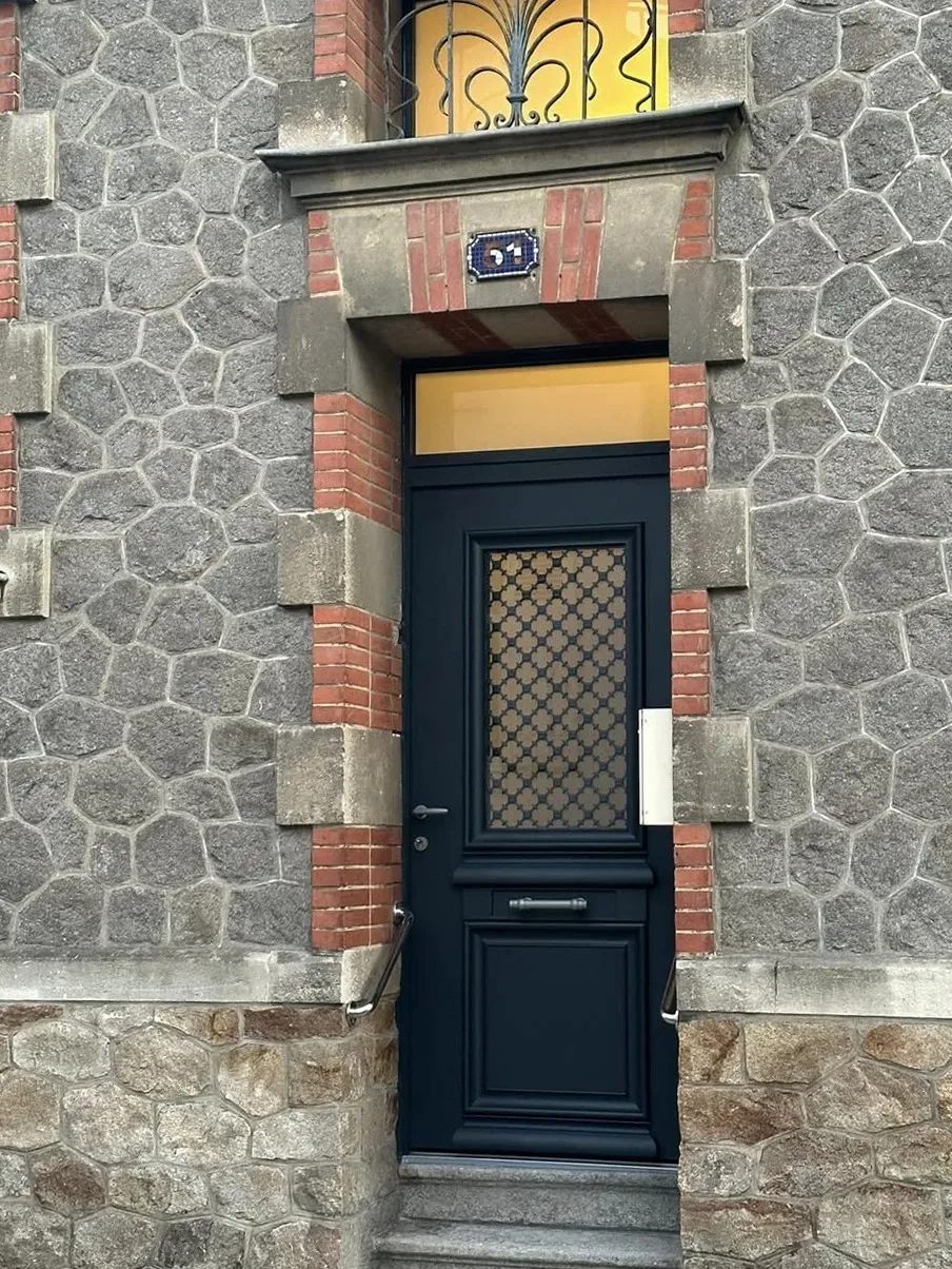 Porte d'entrée noire style traditionnel avec imposte sur façade pierre