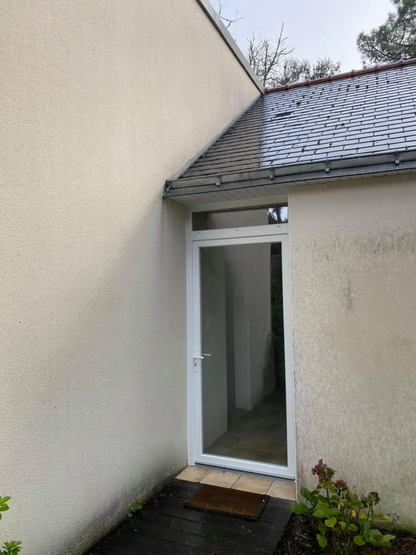 Porte d'entrée PVC blanche vitrée sur maison crépie en rénovation