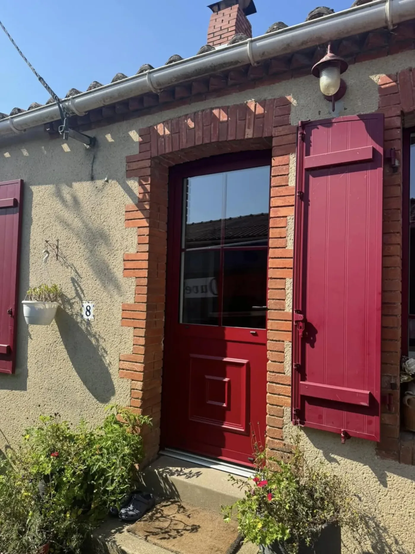 Porte d'entrée rouge bordeaux avec volets battants assortis brique