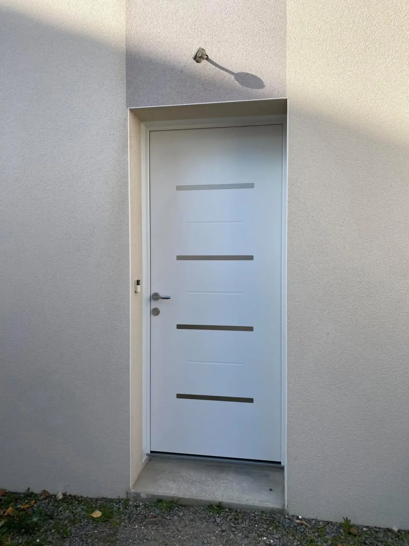 Porte d'entrée aluminium blanc design inserts inox sur crépi