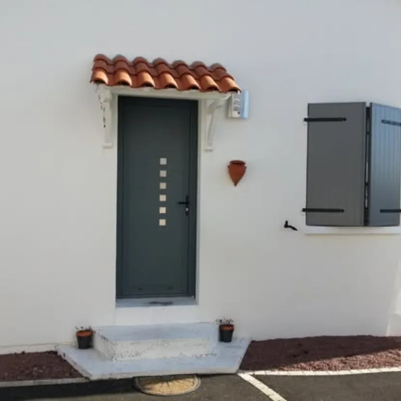 Porte d'entrée gris anthracite avec inserts inox sous auvent en tuiles