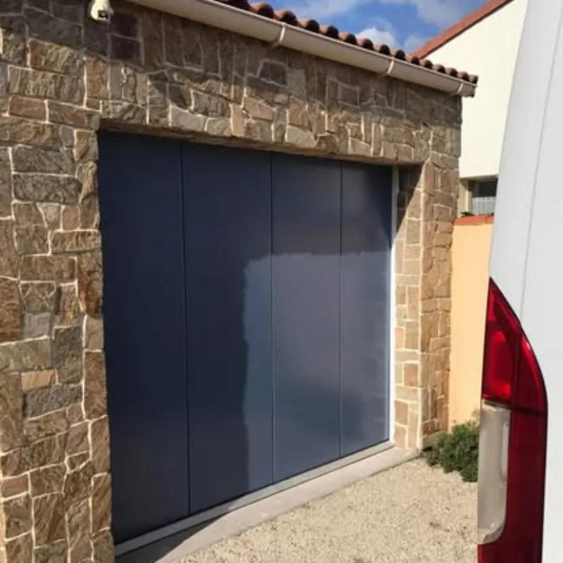 Porte de garage latérale aluminium gris sur façade en pierre
