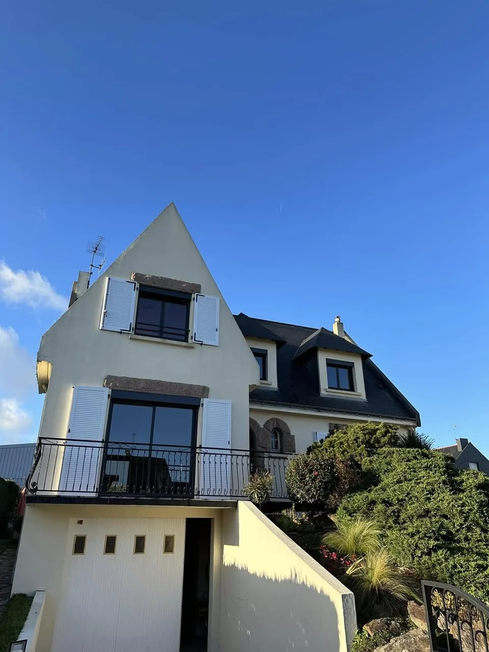 Maison bretonne avec volets battants blancs sur fenêtres et baie vitrée