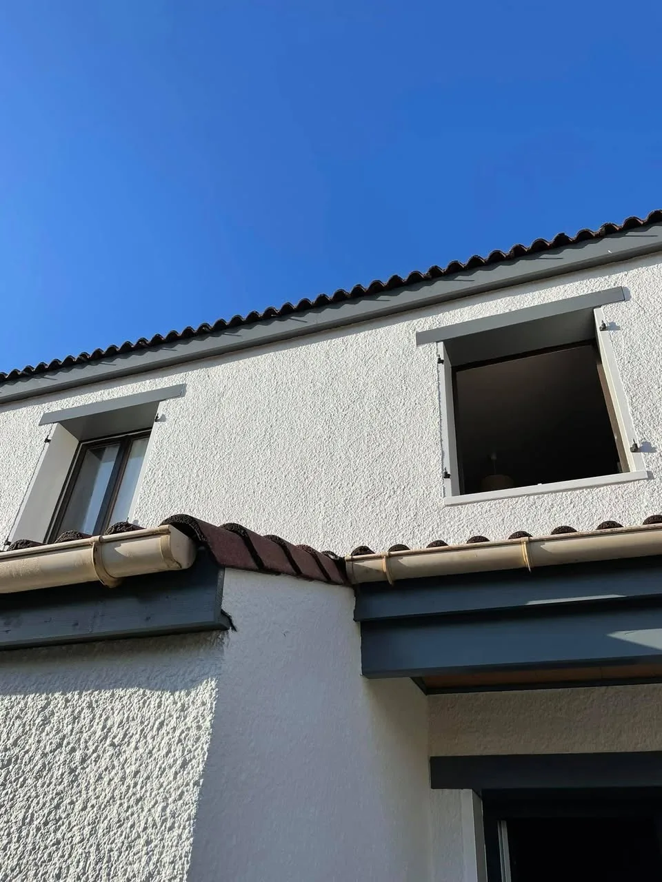 Façade avec volets battants gris anthracite ouverts en rénovation